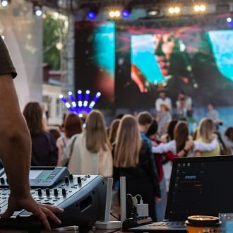 Dj mixing, laptop outdoors at party festival with crowd of people in background. Fun, summer, youth, nightlife, music and entertainment concept. low light. selective focus. professional DJ music mixer